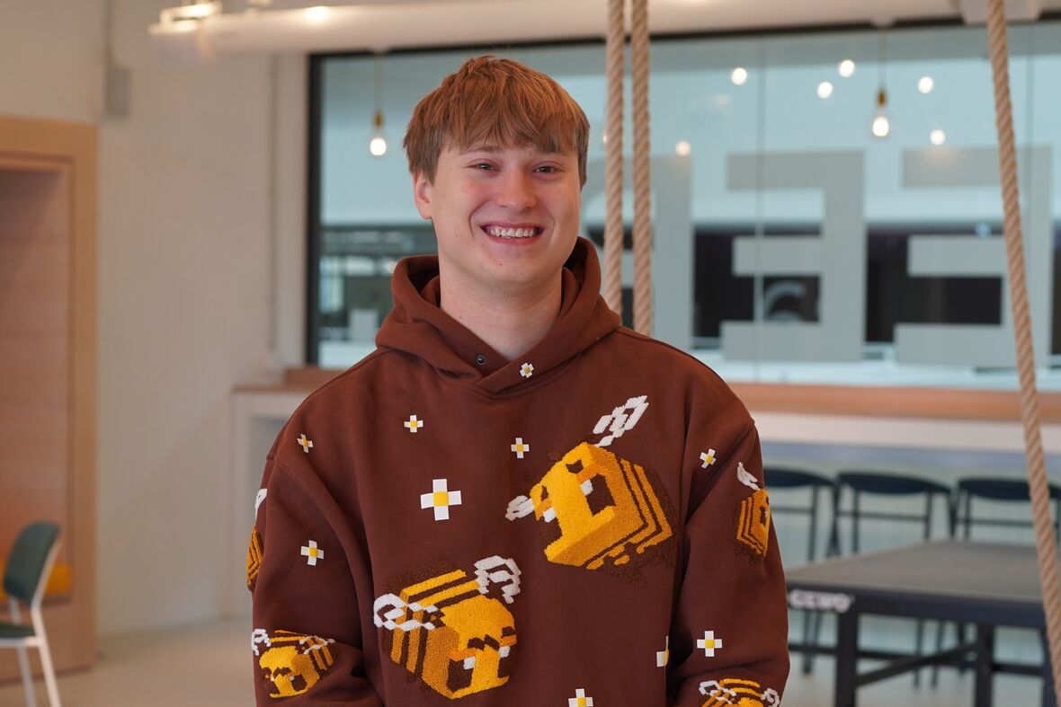 Unser Auszubildender Max sitzt im Social Space und lächelt in die Kamera