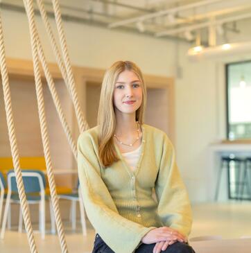 Lina, Auszubildende E-Commerce bei OTTO sitzt im Social Space und lächelt in die Kamera