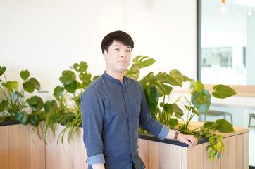 Unser Azubi E-Commerce-Management steht im Social Space und schaut in die Kamera