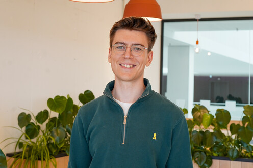 Autorenbild René ReHo Autorenbild des jungen Techblog-Autoren René in einem dunkelgrünen Pullover mit Brille. Der Autor lächelt freundlich und befindet sich in einem Raum mit Pflanzen und orangen Hängelampen. Der Autor befindet sich im OTTO-Headquater.