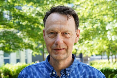 Das Bild zeigt den Techblog-Autor Andreas Nacke in einem blauen Hemd vor einem Baum auf dem OTTO-Campus