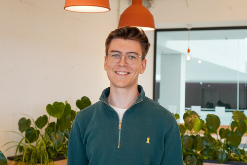 Autorenbild René ReHo Autorenbild des jungen Techblog-Autoren René in einem dunkelgrünen Pullover mit Brille. Der Autor lächelt freundlich und befindet sich in einem Raum mit Pflanzen und orangen Hängelampen. Der Autor befindet sich im OTTO-Headquater.