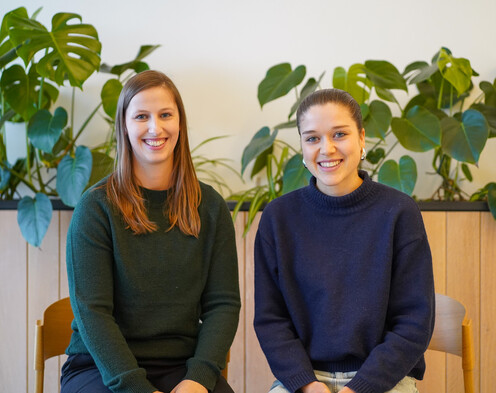 Tech-Blog Autorinnen Aemilia Klingelhöfer & Svenja Lippke Zwei weibliche Autorinnen vor einer Wand mit Pflanzen in warmem Licht