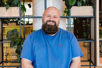 JaVe Foto von Techblog-Autor Jan in einem blauen Shirt, sitzend vor einem Regal mit Pflanzen