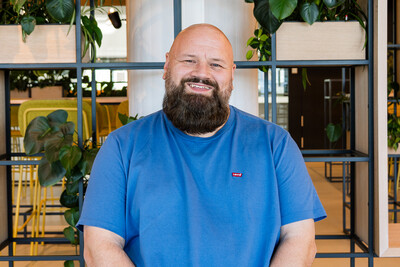 JaVe Foto von Techblog-Autor Jan in einem blauen Shirt, sitzend vor einem Regal mit Pflanzen