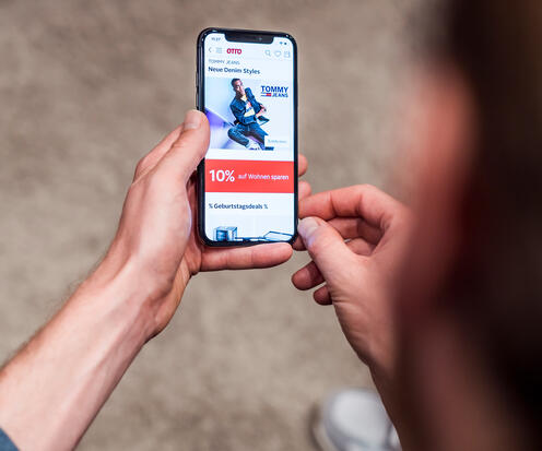 Eine Person ist am Handy, hat die OTTO-App geöffnet und scrollt.