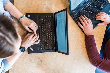 Zwei Kollegen mit Laptops Zwei Kollegen sitzen sich mit ihren Laptopen gegenüber und tippen darauf.