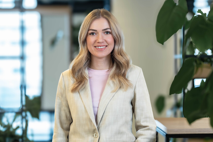 Sophia, Recruiterin bei OTTO, steht im Social Space auf dem OTTO Campus und lächelt freundlich in die Kamera