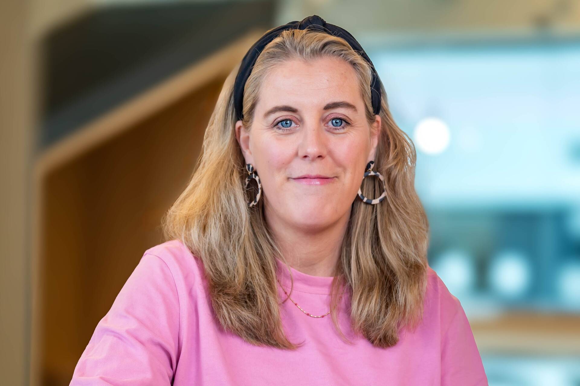 Hannah, Recruiterin bei OTTO, im Social Space auf dem OTTO Campus und lächelt in die Kamera. 