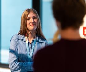 Azubi im Bereich E-Commerce Management befindet sich auf den Starter Days und hört aufmerksam zu mit verschränkten Armen.