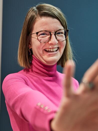 Führungskraft im Bereich IT Eine Kollegin mit Brille und schulterlangen Haaren lächelt in die Kamera.