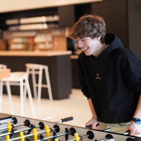 Zwei Azubis spielen konzentriert Tischkicker in einem unserer Social Spaces im OTTO-Headquarter