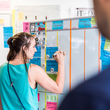 Eine Kollegin arbeitet am Scrum-Board Unsere Kollegin Sarah arbeitet am Scum-Borad