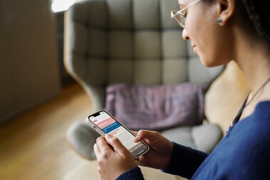 Benefit Check Unsere Kollegin schaut auf ihr Handy und scrollt auf der Karriereseite von OTTO.