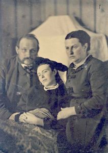 Viktorianische Post-Mortem-Fotografie eines Ehepaares mit ihrer toten Tochter. Der Körper wurde so fixiert, dass sie nahezu lebendig wirkt.