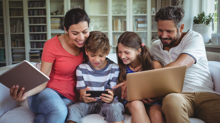 WLAN: Sicherheit und Schutz für dein Funknetzwerk Familie surft mit Smartphone, Tablet und Laptop im WLAN