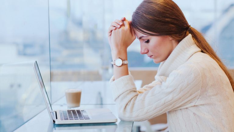 Frau sitzt erschöpft vor dem Laptop