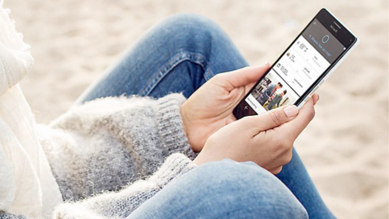 Nutzerin hält Smartphone mit aktivierter Cortana-App in der Hand