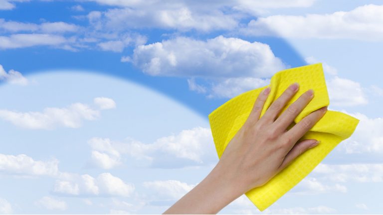 Hand wischt mit Putztuch Scheibe frei