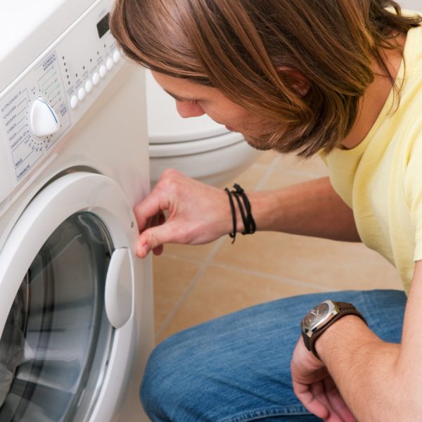 Mann sitzt vor verschlossener Waschmaschine