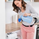 Frau füllt flüssiges Waschmittel in einen Messbecher