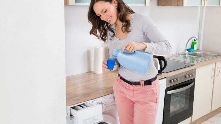 Frau füllt flüssiges Waschmittel in einen Messbecher