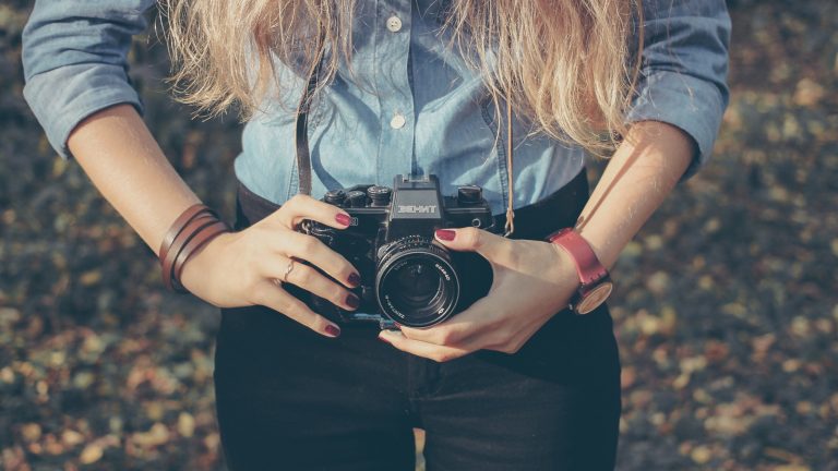 Frau h&auml;lt Kamera in den H&auml;nden