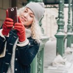 Eine Person ist im Winter drau&szlig;en und macht mit dem Handy Fotos.nter drau&szlig;en und macht mit dem Handy Fotos.