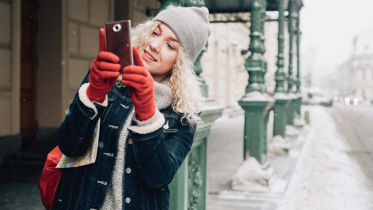 Eine Person ist im Winter drau&szlig;en und macht mit dem Handy Fotos.nter drau&szlig;en und macht mit dem Handy Fotos.