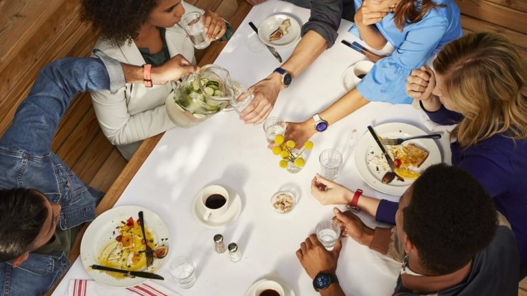 Gruppe von jungen Menschen bei gesunder Mahlzeit, alle mit Smartwatch am Arm