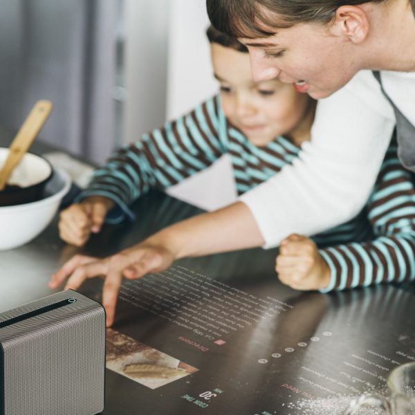 Mutter und Tochter beim Kochen mit projizierter Kochanleitung auf der Arbeitsfl&auml;che