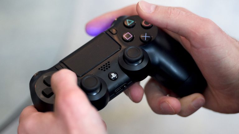 Hand bedient eine Sony PlayStation 4 über einen Controller.