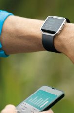 Fitbit Betatest Sportler mit Fitnesstrecker und App auf Smartphone