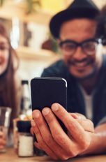 Pinterest stellt „Entdecken ohne Tippen“ vor und kauft neue Plattform Gruppe schaut erfreut auf Smartphone.