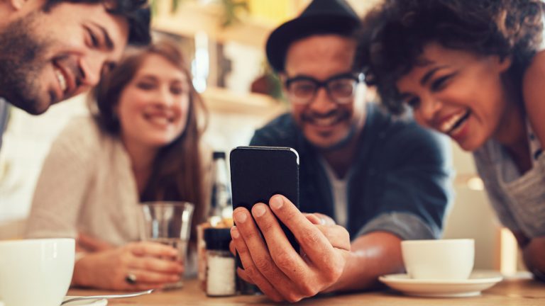 Gruppe schaut erfreut auf Smartphone.