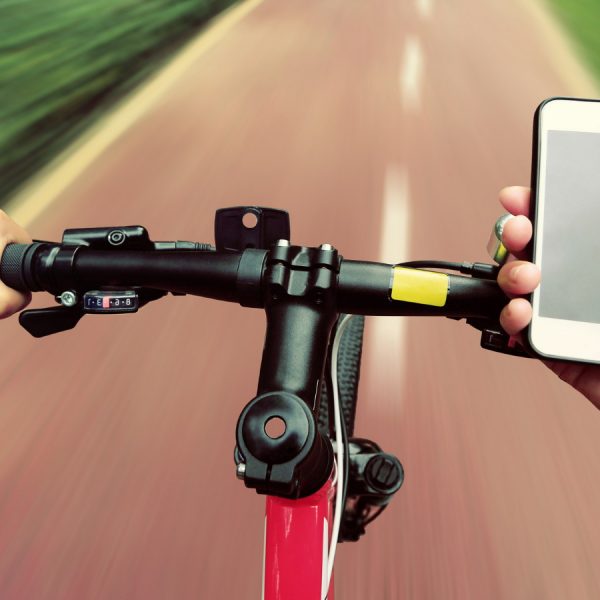 Fahrradfahrer st&uuml;tzt Hand auf Lenker, um Smartphone zu bedienen.