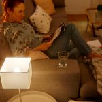 Frau sitzt auf Sofa mit eingeschalteter Lampe