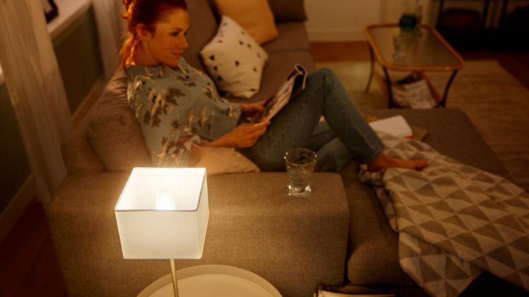 Frau sitzt auf Sofa mit eingeschalteter Lampe