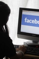 Eine Frau sitzt am Computer, auf dem Facebook läuft
