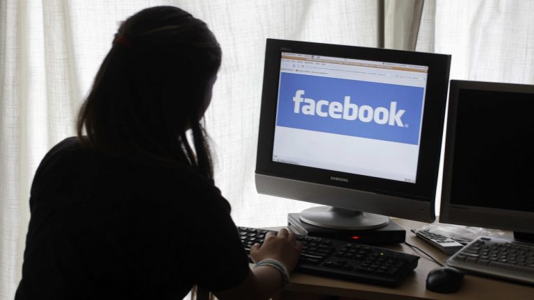 Eine Frau sitzt am Computer, auf dem Facebook läuft