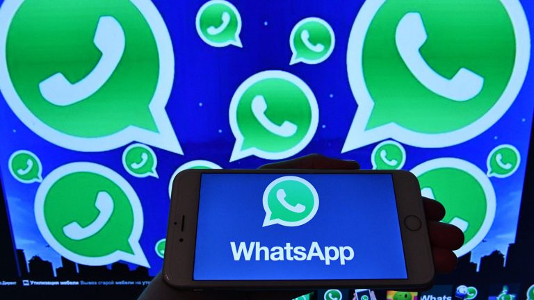 WhatsApp-Logo auf Bildschirm und Smartphone