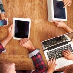 Familie mit Apple-Ger&auml;ten am Tisch nutzt Apple-Familienfreigabe
