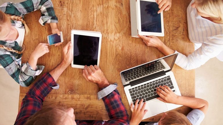 Familie mit Apple-Ger&auml;ten am Tisch nutzt Apple-Familienfreigabe