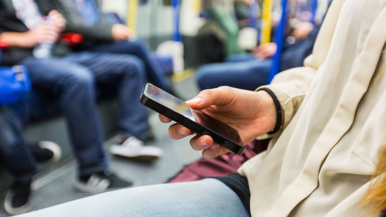 Mann mit Smartphone in der Bahn