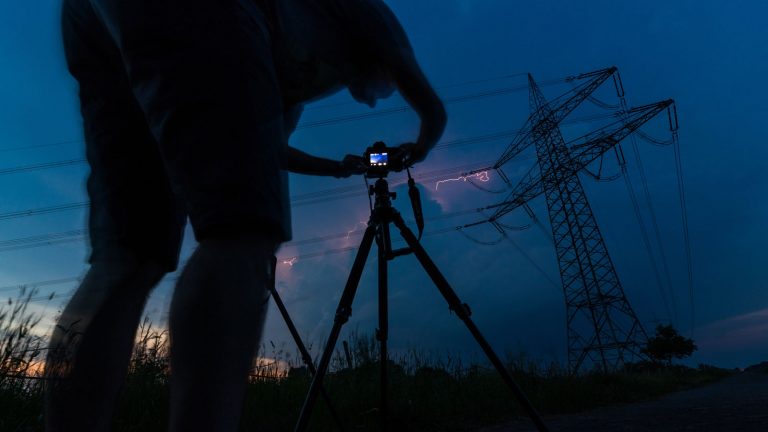 Fotograf mit Kamera im Dunkeln fotografiert Blitz