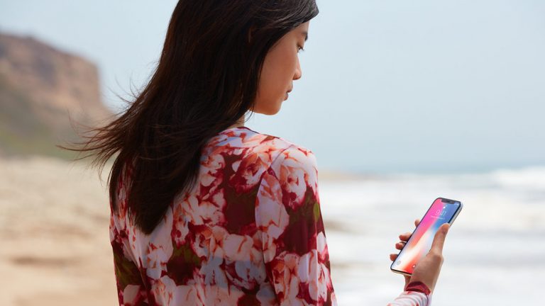 Frau am Strand mit iPhone X