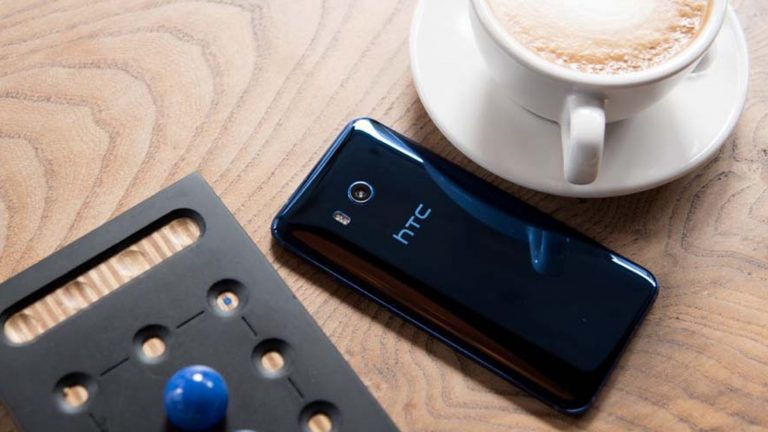 Das HTC U11 liegt mit dem Display auf dem Tisch zusammen mit einer Tasse Kafee