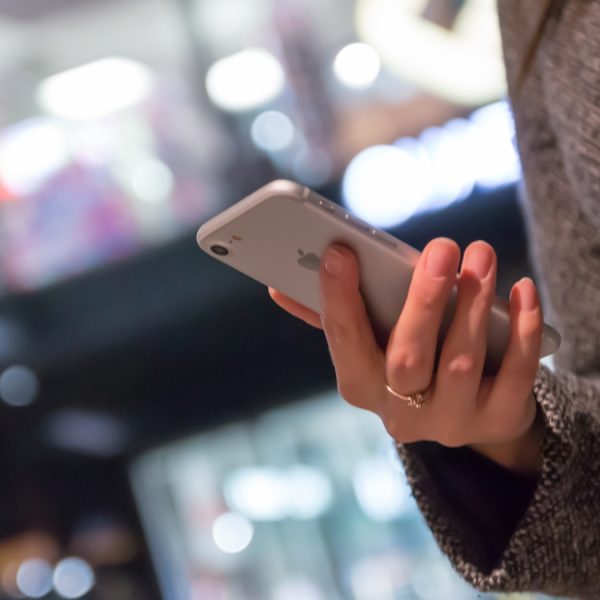 Frau geht mit iPhone shoppen und zahlt mit PayPal