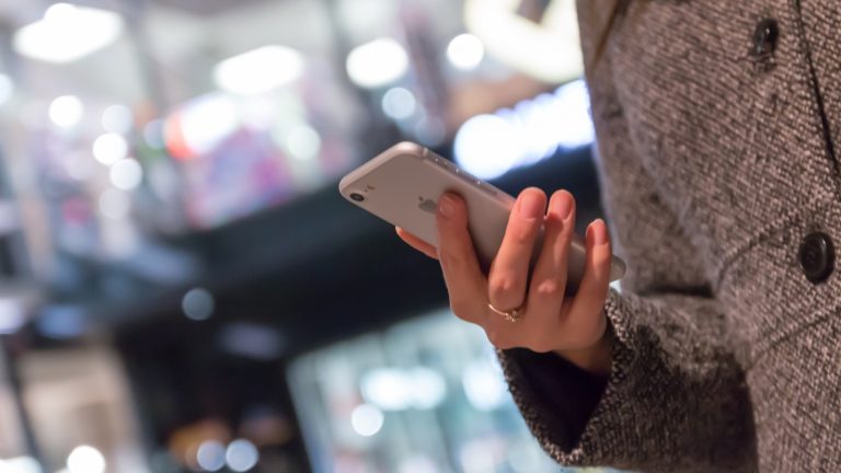 Frau geht mit iPhone shoppen und zahlt mit PayPal