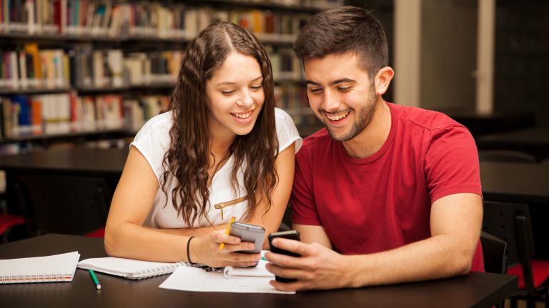 Paar mit Smartphones in Bibliothek